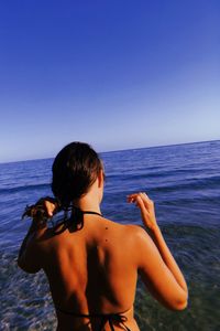 Rear view of shirtless man in sea against clear sky