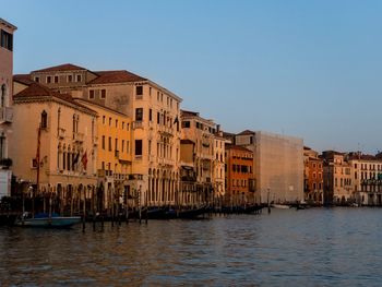 Buildings by canal against sky in city