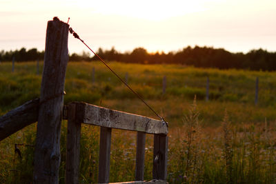 Wooden post on field against sky during sunset