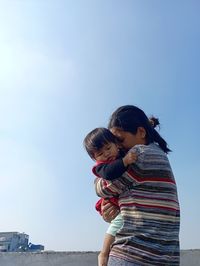 Low angle view of mother-daughter  against clear sky