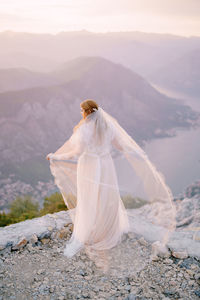 Rear view of woman standing on mountain against sky