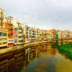 Buildings by river against sky in city