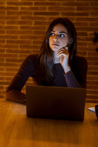 Young woman using laptop while sitting on table