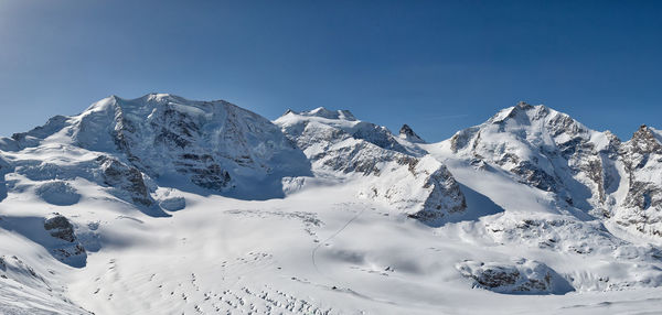 Scenic view of snowcapped mountains against clear blue sky