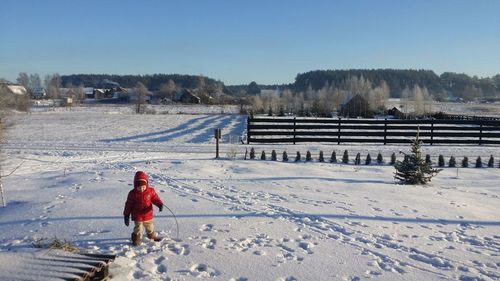 Woman on snow covered field against sky