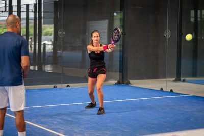 Monitor teaching padel class to woman, his student - trainer teaches young girl how to play padel 