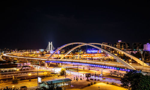 Light trails on bridge in city against clear sky at night