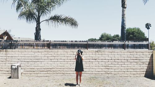 Woman taking photographs in front of wall