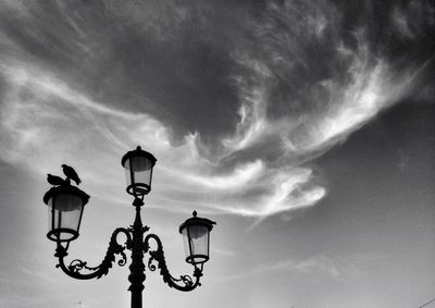 Low angle view of street light against cloudy sky