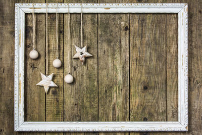 Christmas decorations hanging from picture frame mounted on wooden wall