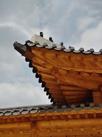 Low angle view of cross on roof of building against sky