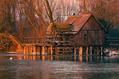 Waterwheel by stilt house on lake