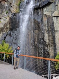Man standing on rock against waterfall