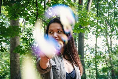 Portrait of woman standing against trees