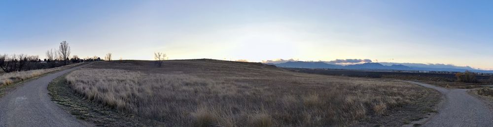 Panoramic view of road amidst field against sky