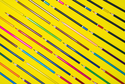 Colorful pencils arranged on yellow background