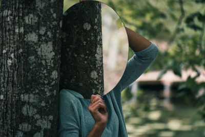 Close-up of person hand holding tree trunk in forest