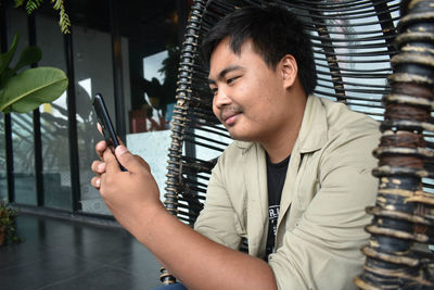 Young man using smart phone while sitting on swing