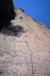 Man climbing on rock against clear sky