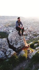 Full length of young man standing on rock against sky