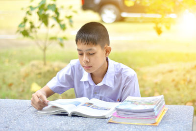 Boy reading book while sitting at park