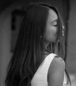 Mid adult woman with eyes closed standing against wall outdoors