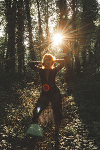 Rear view of woman standing in forest