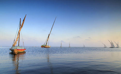 Boats moored on sea at sunset
