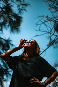 Low angle view of woman standing against trees