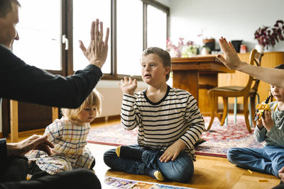 Parents doing high-five with son having down syndrome sitting in living room at home