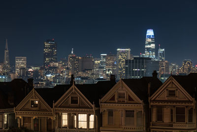 Illuminated buildings in city against clear sky at night