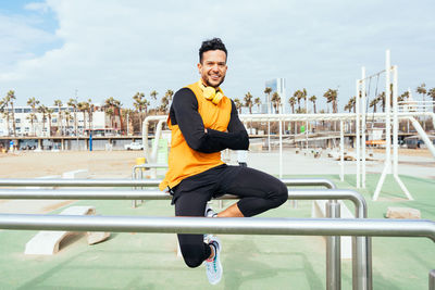 Portrait of young man sitting on gymnastics bar