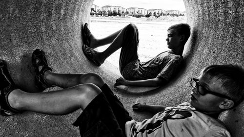 Boys lying in concrete pipe