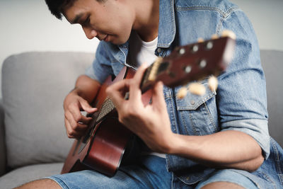 Midsection of man playing guitar