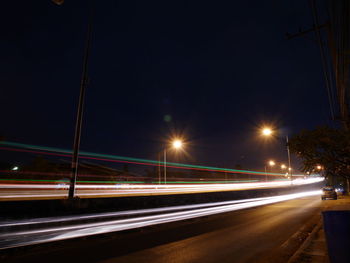 Light trails on road against sky at night