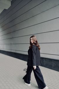 Portrait of young woman standing against wall