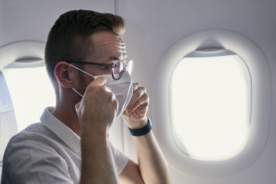 Passenger wearing protective face mask in airplane. 