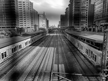 Railroad tracks amidst buildings in city against sky