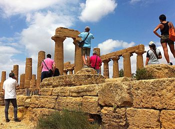 Tourists on top of historic building against sky