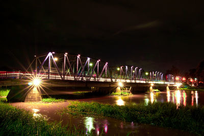 Illuminated bridge over river at night