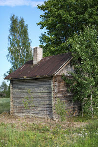 Old house on field against trees