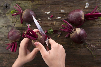 Cropped image of woman cutting beetroot on table