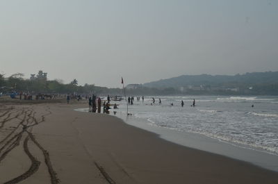 Group of people on beach against clear sky