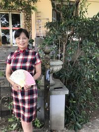 Portrait of smiling woman standing by plants