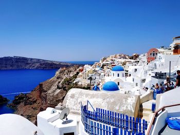 Buildings by sea against clear blue sky