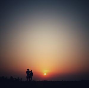 Silhouette people standing on field against sky during sunset