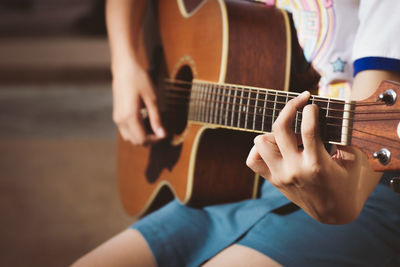 Midsection of woman playing guitar