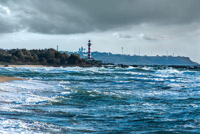 Lighthouse by sea against sky