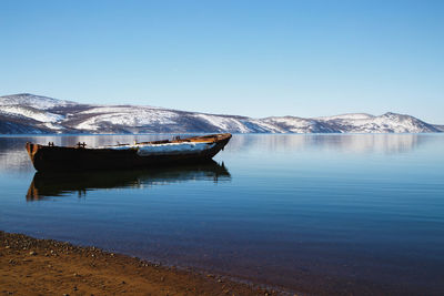 Scenic view of lake by snowcapped mountains against clear blue sky