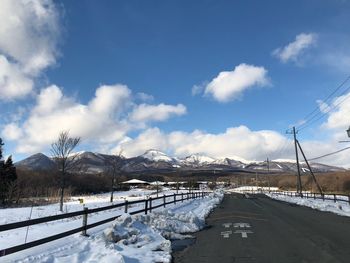 Road by snow covered mountain against sky